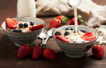 Wall Mural - Healthy breakfast. Milk pouring into bowl of muesli with fresh berries