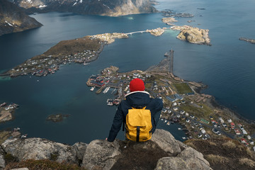 Fototapete - Man sitting on cliff edge alone enjoying aerial view backpacking lifestyle travel adventure outdoor vacations in Norway top of Reinebringen mountain.