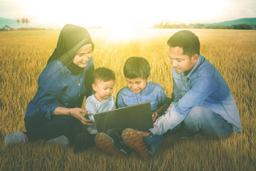 Sticker - Children use a laptop with their parents in meadow