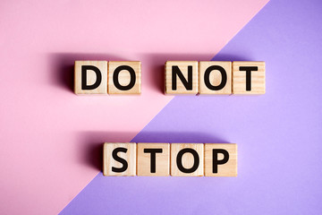 Fototapete - phrase do not stop, wooden cubes with letters on color background top view