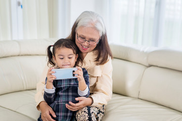 Poster - Cute little girl using a phone with her grandmother