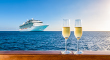 Two Glasses Of Champagne On Wooden Railing At Sunset. Blurred Cruise Ship In The Background. Luxury Travel Vacation.