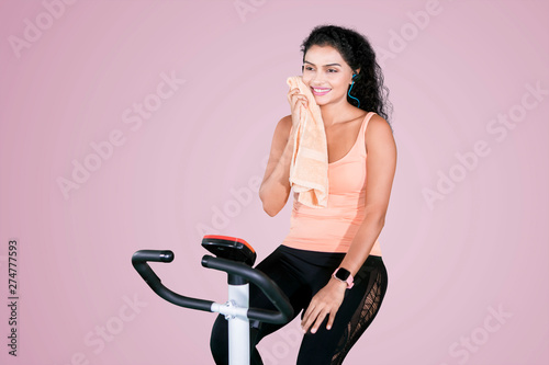 Cuadros en Lienzo Young woman wipes her sweat on an exercise bike