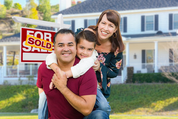 Happy Mixed Race Family In Front of House and Sold For Sale Real Estate Sign