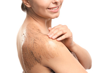 Beautiful young woman applying body scrub against white background, closeup