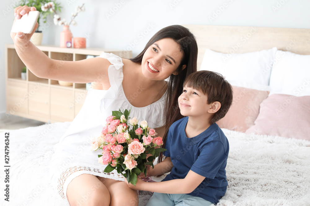 Happy mother and son taking selfie at home