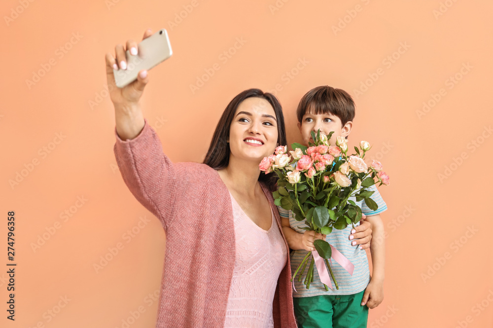 Happy mother and son taking selfie on color background