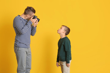 Poster - Father taking photo of his little son on color background