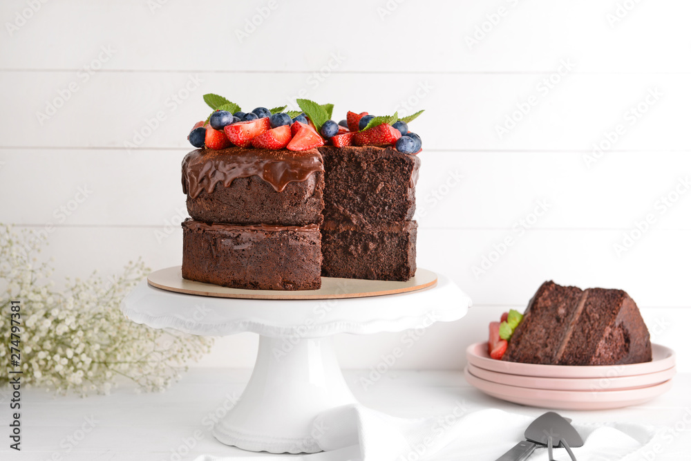 Stand with tasty chocolate cake on white table