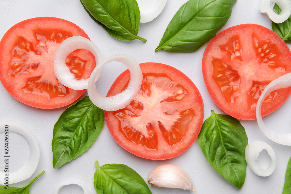 Fresh basil, tomato, onion and garlic on light background