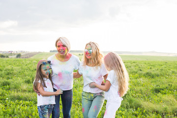 Friendship, Indian holidays and people concept - young women and children having fun on the summer field on festival of holi