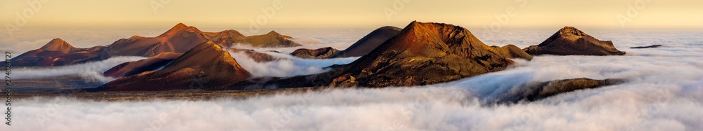 Volcanoes in the Timanfaya national park on Lanzarote. Volcanoes rising out of the clouds - obrazy, fototapety, plakaty 