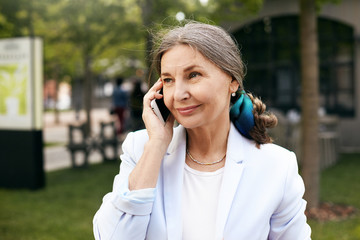 elegant attractive mature businesswoman wearing white jacket and headscarf in her gathered hair smil