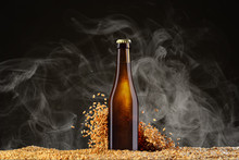 Brown Beer Bottle With Reflections On A Smoke Black Studio Background With Scattering Wheat Corns.