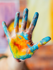 Modern fine art performance. Closeup of hand dirty with blue and yellow paint. Blur background.