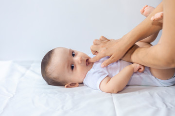 baby boy teething pain. little 6-month baby having teeth pains. mother rubbing gel to her little bab