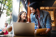 © NDABCREATIVITY - Young couple is working in cafe on laptop and smiling.