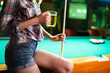 © NDABCREATIVITY - Young beautiful woman having fun and playing billiard in a club