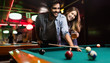 © NDABCREATIVITY - Young couple playing snooker together in bar