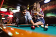 © NDABCREATIVITY - Happy young man playing snooker with his girlfriend. Happy loving couple.