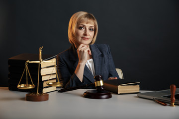 Female jurist isolated at the dark background. Books and gavel with justice scales