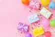 © juliasudnitskaya - Gift or present boxes, colorful balloons and confetti on pink pastel table top view. Birthday party background. Banner format.