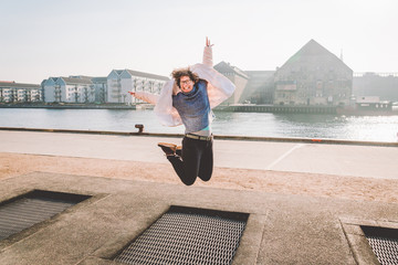 adult person rejoices like child. Playground trampoline in ground, children trampoline, springs throws people up fun and cool. Copenhagen River Embankment Denmark. Woman jumping on street trampoline