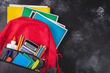 Backpack With School Supplies on a Blackboard Background