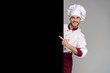 © opolja - Image of smiling young cook in uniform standing isolated over grey wall background. Looking camera pointing.
