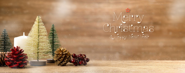 Poster - Merry christmas and happy new year word over Christmas tree decoration on wood table with snow.pine cone,mistletoe and bell ball hanging with blur wood wall background.Holiday greeting card