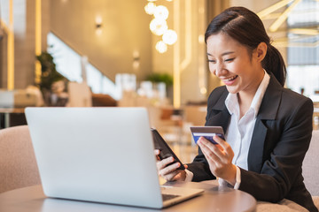 Asian businesswoman using credit card and mobile phone for online financial payment and shopping