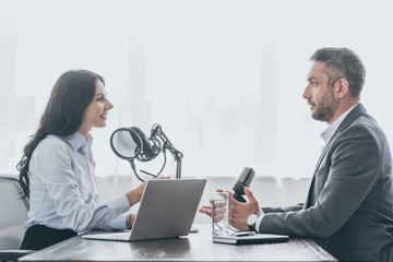 handsome businessman talking to pretty radio host during interview in radio studio