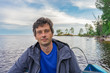 © Tatyana_Andreyeva - Handsome middle-aged man sitting at boat stern and floating along northern river on beautiful landscape background at sunset. Travel concept. Onega lake, Karelia, Russia