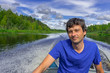 © Tatyana_Andreyeva - Handsome middle-aged man sitting at boat stern and floating along northern river on beautiful landscape background in summer day. Travel concept. Chernaya river, Karelia, Russia