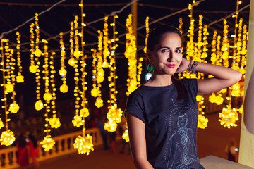 Wall Mural - Beautiful young woman resting in an amusement Park. Concept of summer festivals, recreation and entertainment. Yellow illumination in the background