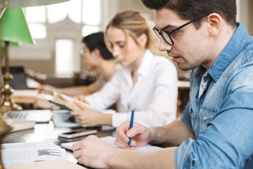 Canvas Print - Group of smart young students studying hard