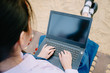 © TeTe Song - Top view of lovely teenage girl wearing school uniform sitting on swing in the park on the sand with laptop, notebook, hands on keyboard.