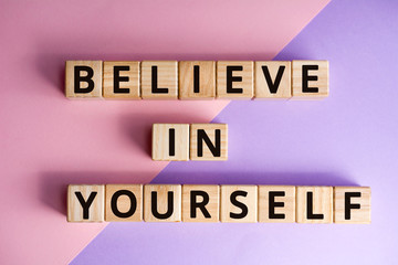 Fototapete - phrase believe in yourself, wooden cubes with letters on color background top view