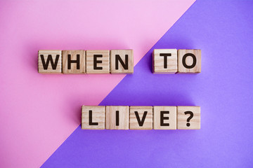 Fototapete - phrase when to live? wooden cubes with letters on color background top view