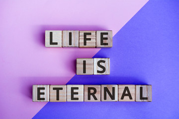 Fototapete - phrase life is eternal, wooden cubes with letters on color background top view