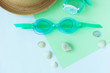 © KawaiiS - Summer flatlay with watersport goggles, hat, watch on mint and light blue background, minimalistic style, copy space.