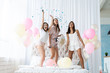 © opolja - Yeah! Four attractive young women in pajamas smiling and gesturing while jumping in the bedroom with confetti flying everywhere
