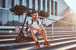 © Fxquadro - Pensive attractive man is sitting on the stairs with his electric scooter at bright sunny day.