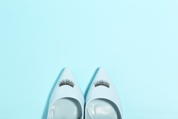 Sticker - High heeled shoes with eyelashes on blue background. Minimalism concept