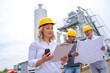 © Drpixel - Woman civil engineer on site visiting concrete plant with two colleagues with blueprint in the background