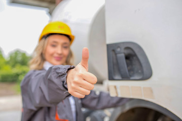 Wall Mural - Woman, truck driver, with thumb up, standing in front of the concrete mixer truck