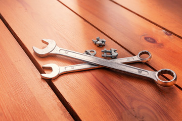 Two wrenches and some bolts are laying on a wooden surface