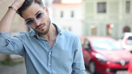 Canvas Print - closeup of a casual young man fixing his hairstyle by passing his hand through his hair in the streets of an old town