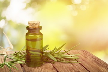 Canvas Print - Oil bottle and green herbs on blue background