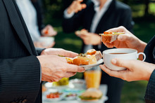 Closeup Of Businesspeople Eating Coffee And Sandwiches During Outdoor Business Lunch